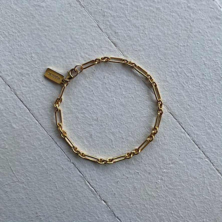 Gold chain bracelet on a light gray surface